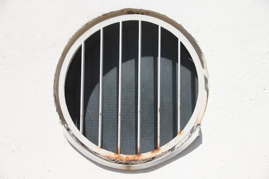 round-window-with-white-bars-on-a-white-wall-e05plrovece