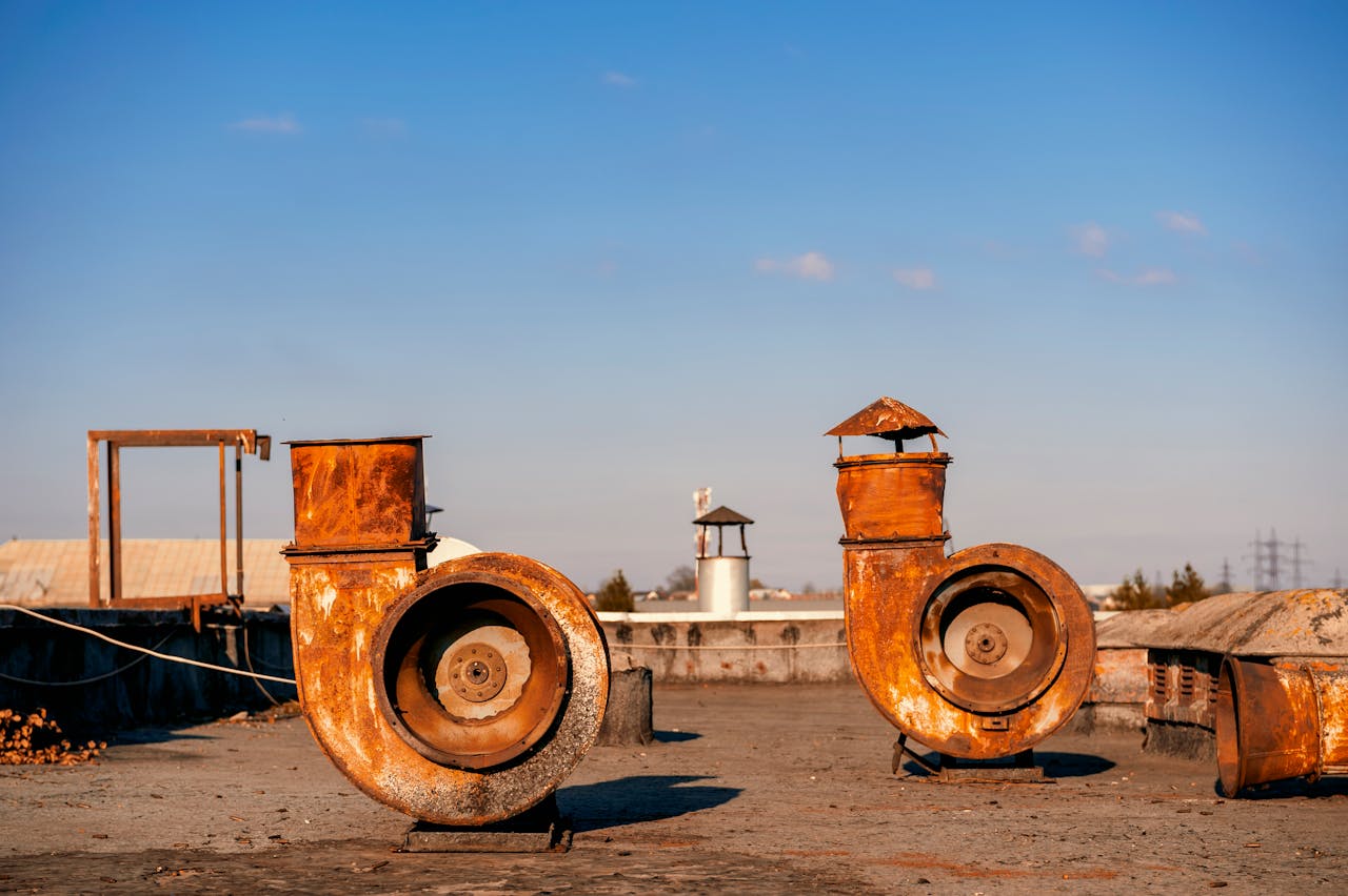 A pair of rusty industrial vent pipes on a rooftop on a sunny day in Lviv, Ukraine.